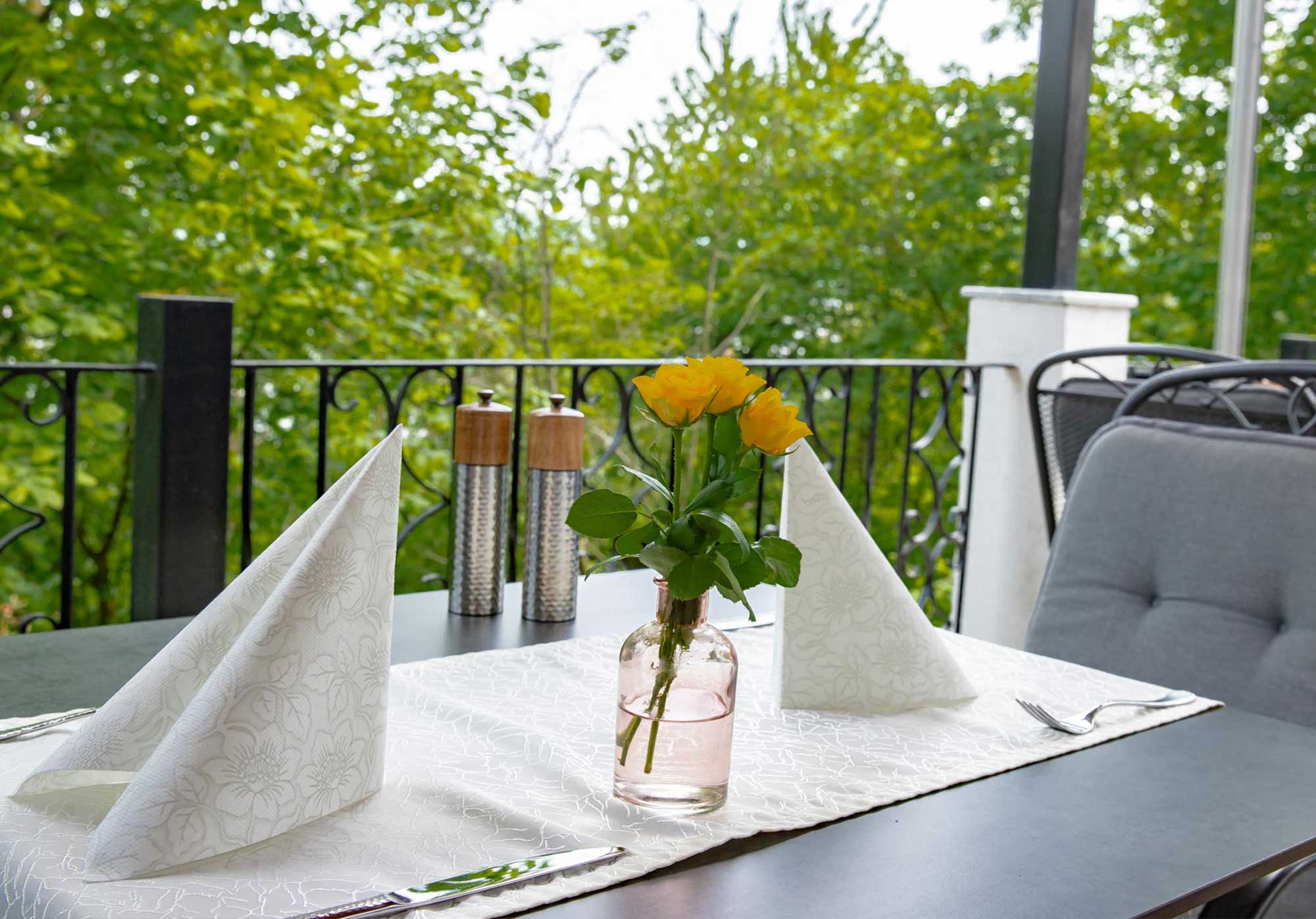 Liebevoll gedeckter Tisch auf der grünen Restaurantterrasse
